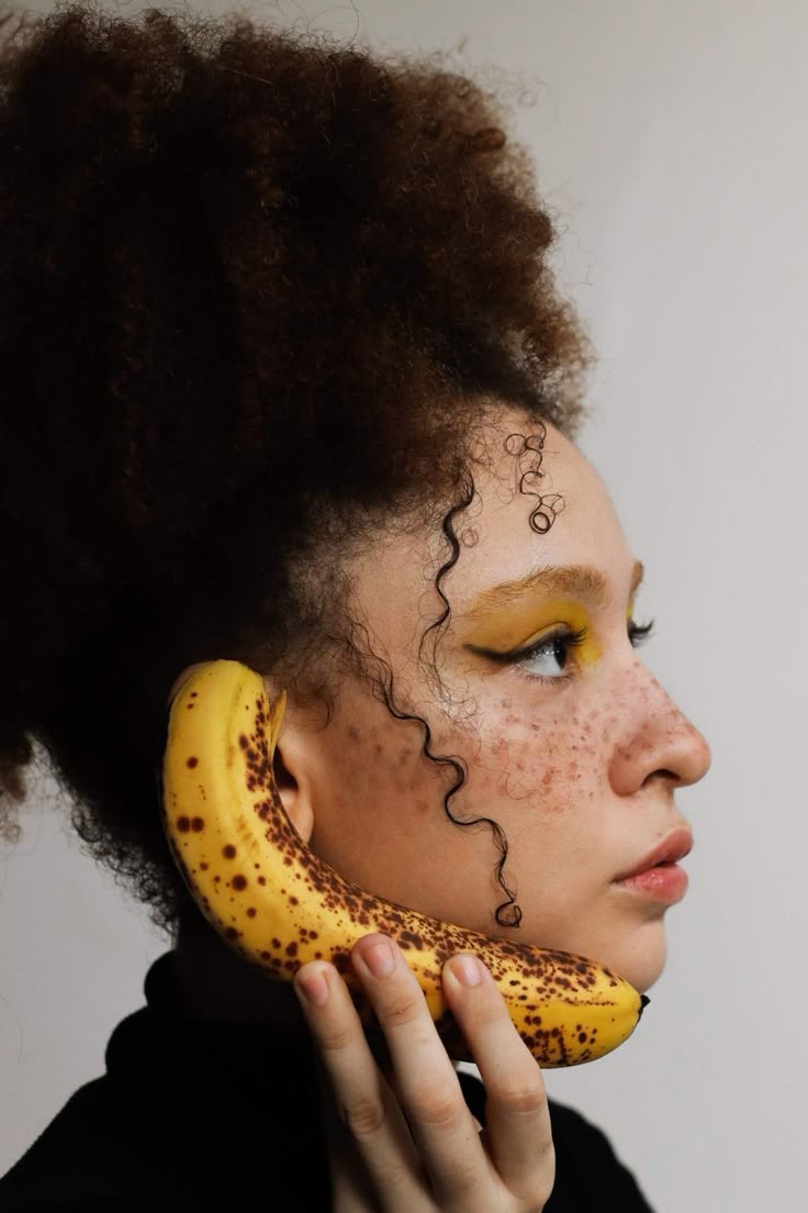 Portrait of a woman holding a ripe banana to her ear like a phone
