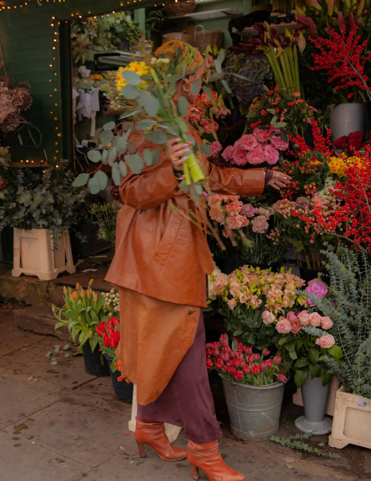 Woman in a tan coat choosing flowers at a market